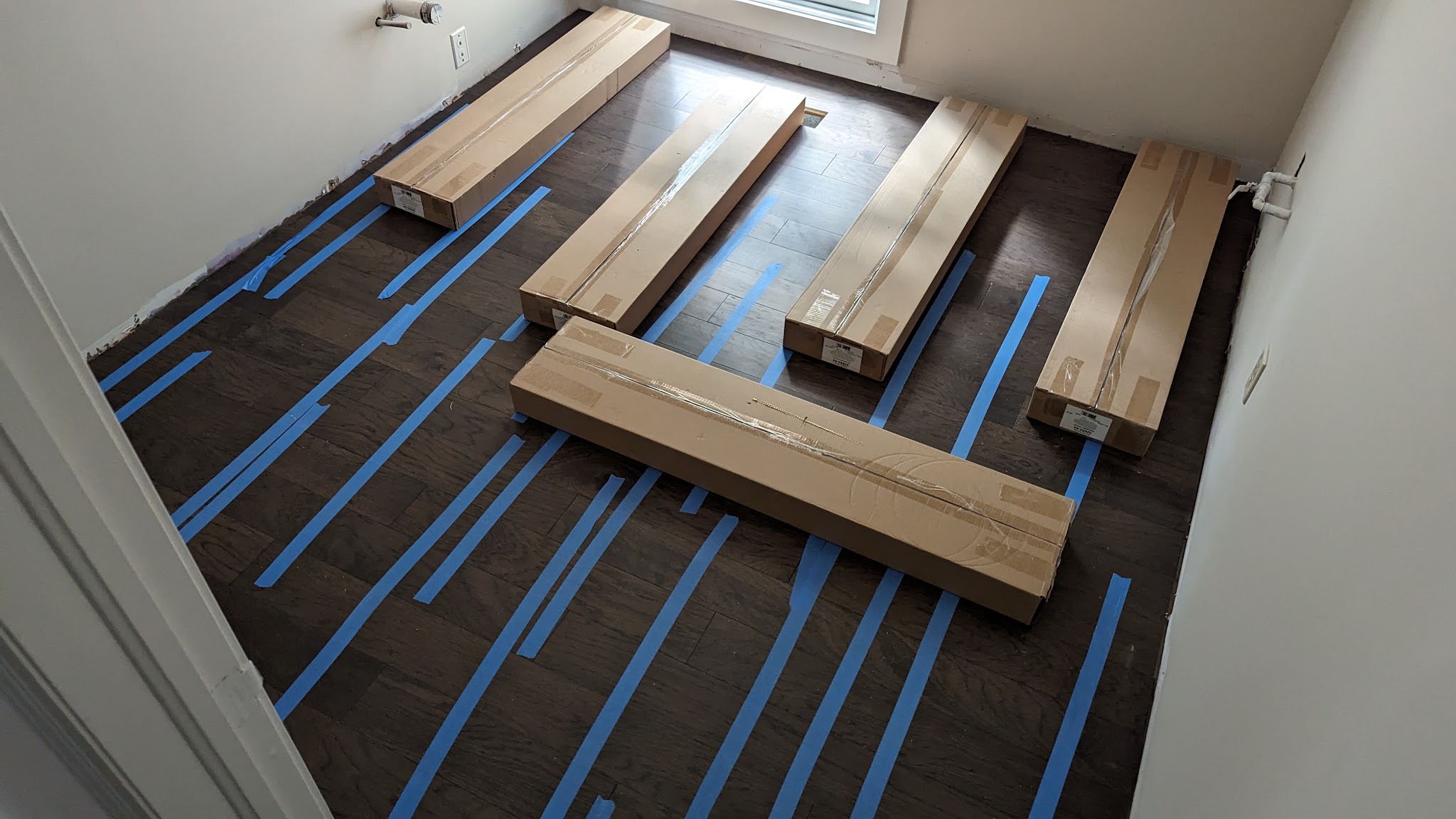 Hardwood boards laid out on a taped subfloor