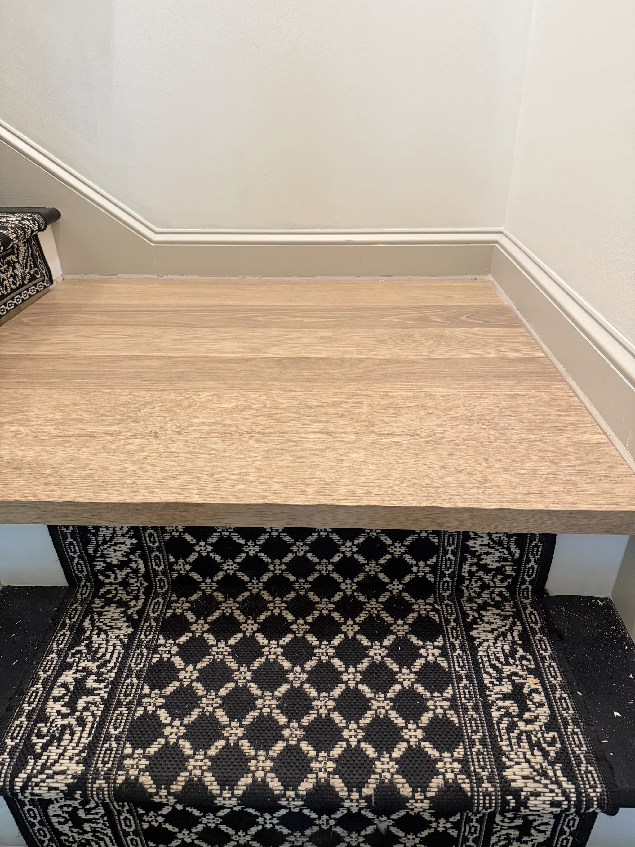 Hardwood landing above a patterned stair runner